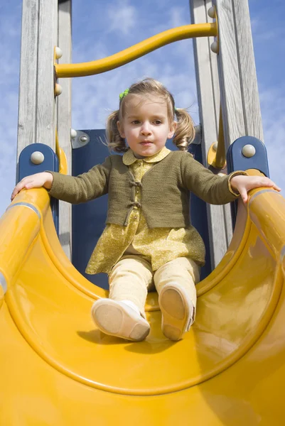 Молодая девушка на горке на детской площадке — стоковое фото