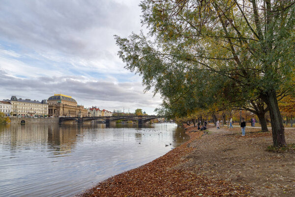 Prague, Czech Republic - 4 November 2025: People on the bank of the Vltava river, on Strelecky island just under Legion Bridge
