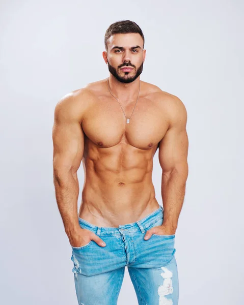 Mavi kotlu, gömleksiz, kaslı adam. Stüdyoda pantalonlu erkek model. Kot pantolon giyen seksi adam..