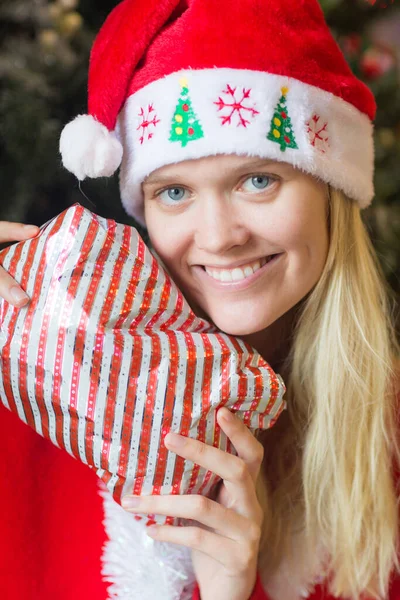 Glückliche Junge Frau Mit Weihnachtsgeschenk Und Roter Mütze Des Weihnachtsmannes lizenzfreie Stockfotos