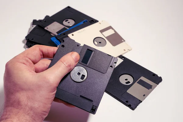 Man showing inside of a floppy disk on scattered floppy disks. Old computer technology from 1980s and 1990s.