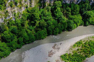 Nehir kenarındaki yol. Dağlar arasında. Yazın gökyüzü parkından AJ Hacket Sochi 'ye bitkiler.
