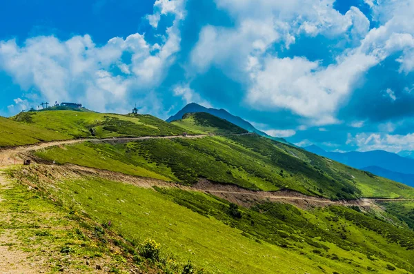 A estrada nas belas montanhas ensolaradas no verão entre os campos — Fotografia de Stock