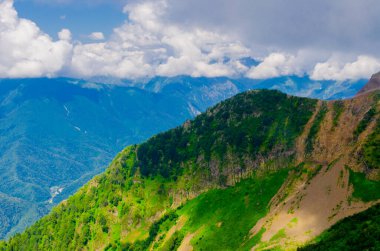 Yazın dağ zirveleri güneşli bir günde bulutlarla birlikte.