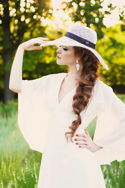 Красива руда дівчина в стильному солом'яному капелюсі в ботанічному саду — стокове фото