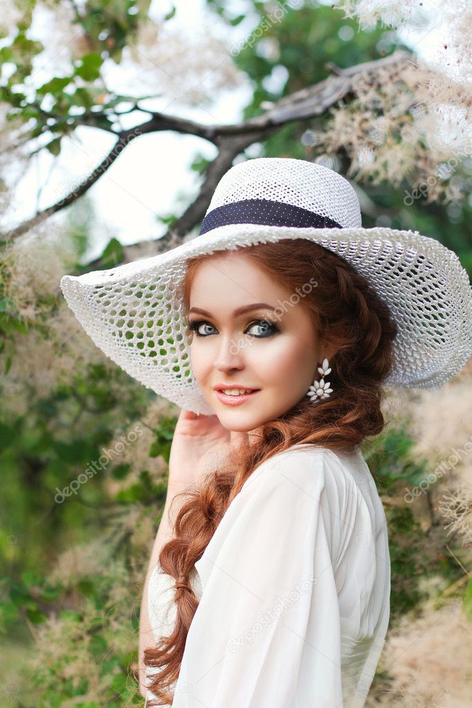 Beautiful red-haired girl in a stylish straw hat