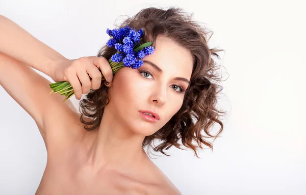 Schönes Mädchen mit frühlingshaften blauen Blumen. isoliert auf einem weißen Bac — Stockfoto