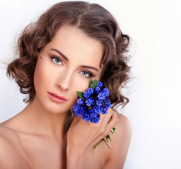 Schönes Mädchen mit frühlingshaften blauen Blumen. isoliert auf einem weißen Bac — Stockfoto