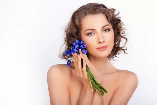 Schönes Mädchen mit frühlingshaften blauen Blumen. isoliert auf einem weißen Bac — Stockfoto