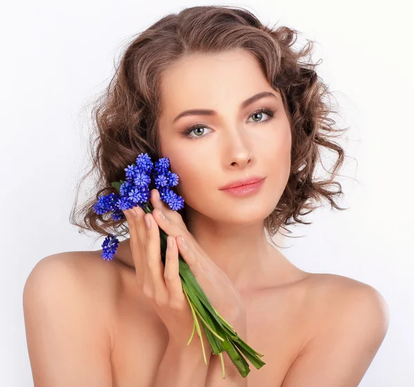 Schönes Mädchen mit frühlingshaften blauen Blumen. isoliert auf einem weißen Bac — Stockfoto