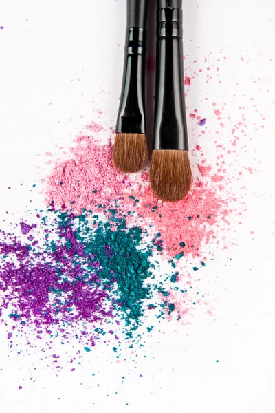 Makeup brushes on white background with colorful powder. Make-up