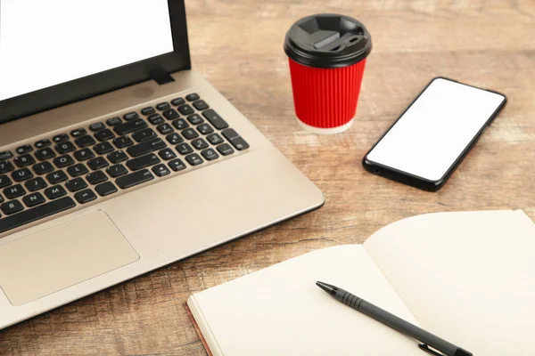 Laptop beyaz beyaz ekran ve ahşap masada akıllı telefon. Yukarıdan bak. Üst görünüm.