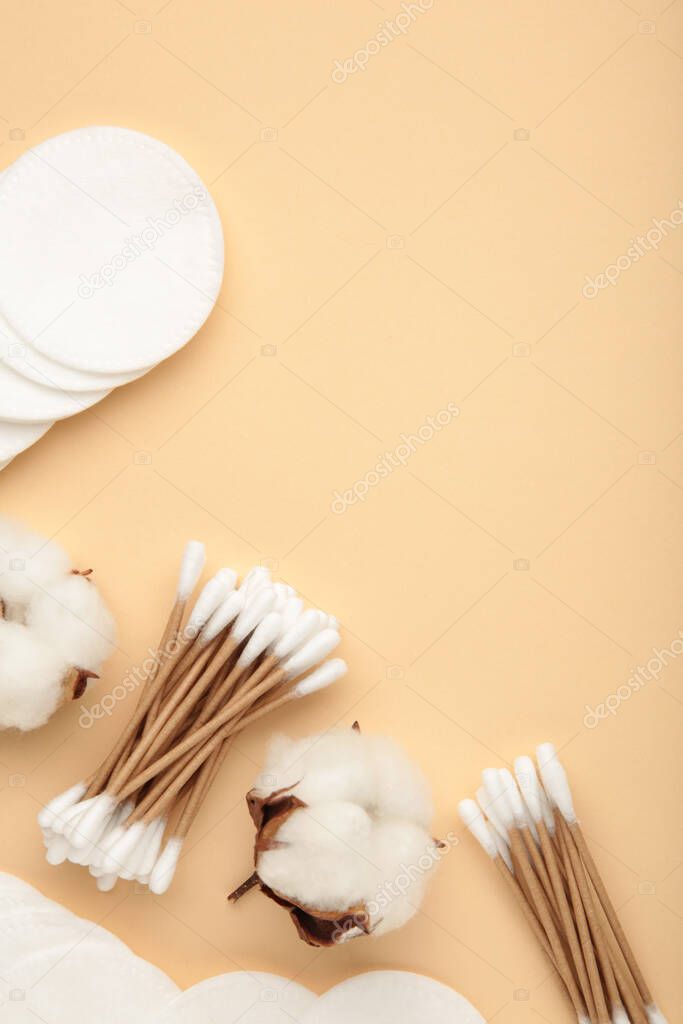 Cotton swabs and sticks with flower on beige background. Top view