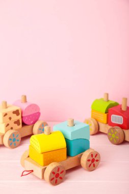 Pembe arka planda, gölge yansıması olan küçük çocuklar için tren oyuncağı istiflemek. Tahta geometrik bloklardan yapılmış bebek treni. Çocuklar için renkli ahşap istifleme treni