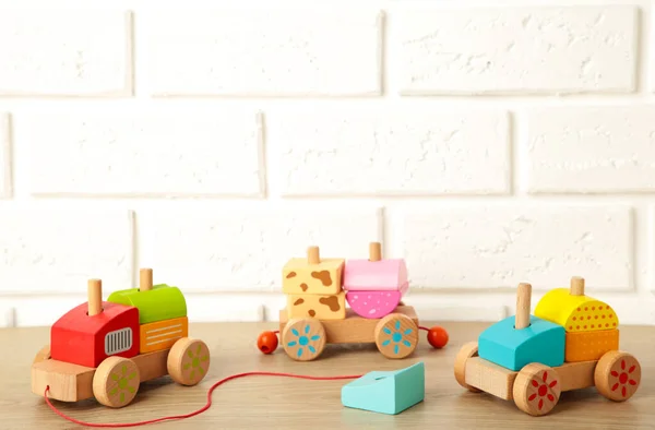 Stacking train toddler toy for little children on light background with shadow reflection. Baby train made of wooden geometric blocks. Colorful wooden stacking train for kids