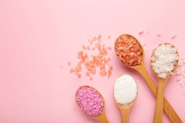 Pembe arka planda tahta kaşıklarda çeşitli spa deniz tuzu çeşitleri. Üst görünüm