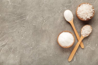 Kasede deniz tuzu ve gri arka planda kaşık. Üst görünüm