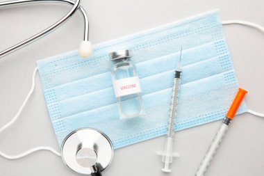 Coronavirus COVID-19 aşı tüpleri, şırınga ve steteskop gri arka planda. Aşı seansı ve dokunulmazlık geliştirme. Covid 19 Üst Görünüm