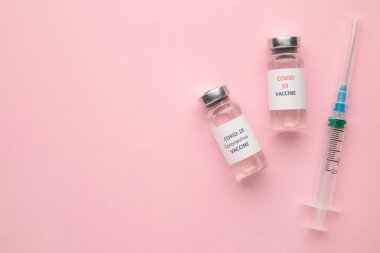 Coronavirus COVID-19 aşı tüpleri ve pembe üzerine fotokopi arkaplanı olan şırınga. Üst görünüm