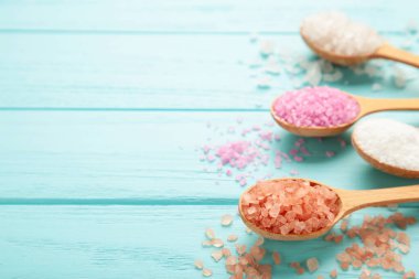 Tahta kaşıklarda mavi ahşap arka planda çeşitli spa deniz tuzu çeşitleri. Üst görünüm