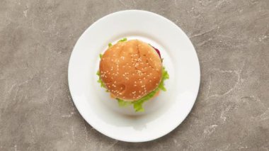 Hamburger beyaz tabakta. Lezzetli hamburger yeme animasyonu, dur hareketi. Fast food konsepti