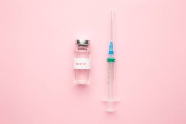 Coronavirus COVID-19 aşı tüpleri ve pembe üzerine fotokopi arkaplanı olan şırınga. Üst görünüm