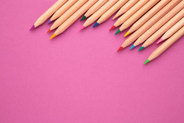 Pembe arka planda renkli kalemler. Üst görünüm.