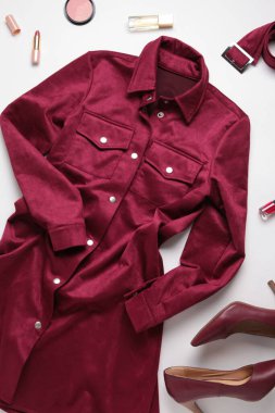 Düz kadın kıyafetleri ve aksesuar kolajı beyaz arka planda bordo bir elbise ile yatıyordu. Üst görünüm