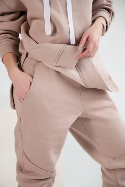Girl in a beige sports suit on grey background. Front view.