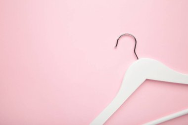 Pembe arka planda ahşap beyaz bir askılık. Dükkan konsepti, boş askı.