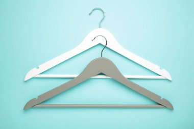 Mavi arka planda beyaz ve gri ahşap askılar. Dükkan konsepti, boş askı.