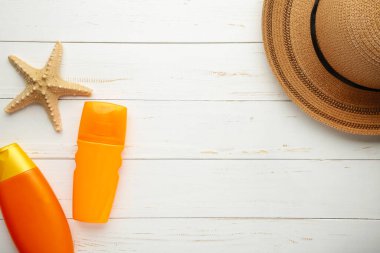 Beyaz arka planda şapka ve kabuklu güneş kremi şişesi. Güneş yanığı için kozmetik. Kopyalama alanı olan güneş koruma kremi
