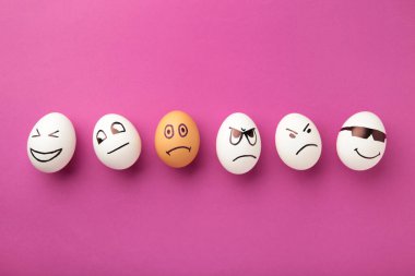 Yüzünde farklı duygular olan yumurtalar. Pembe arka planda fotokopi alanı olan Paskalya kompozisyonu. Irkçılığı bırak. Üst görünüm