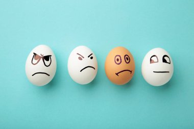 Yüzünde farklı duygular olan yumurtalar. Mavi arka planda fotokopi alanı olan paskalya kompozisyonu. Irkçılığı bırak. Üst görünüm