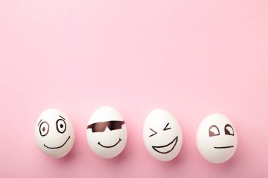 Komik paskalya yumurtaları, pembe arka planda yüzünde farklı duygular var. Paskalya kompozisyonu. Üst görünüm