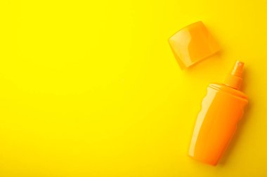 Sarı arka planda güneş koruma şişesi. Yaz tatili. Üst görünüm.