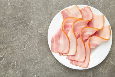Gri arka planda taze çiğ domuz pastırması. Üst görünüm