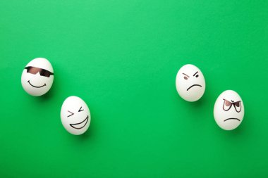 Yeşil arka planda farklı duyguları olan komik Paskalya yumurtaları. Paskalya kompozisyonu. Üst görünüm