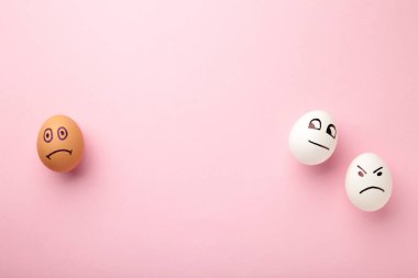 Yüzünde farklı duygular olan yumurtalar. Pembe arka planda fotokopi alanı olan Paskalya kompozisyonu. Irkçılığı bırak. Üst görünüm