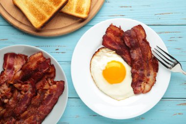 Mavi arka planda kahvaltı için yumurta ve pastırma. İngiliz kahvaltısı. Üst görünüm