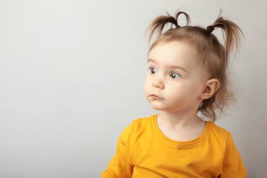 Gri arka planda duran şaşırmış küçük kızın portresi. Üst Manzara. Kapat.