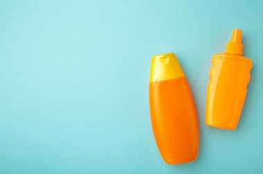 Mavi arka planda güneş kremi şişesi. Güneş yanığı için kozmetik. Üst Manzara, düz çizgi. Kopyalama alanı olan güneş koruma kremi.