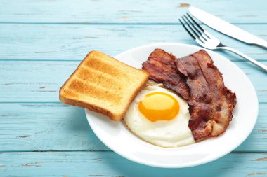 Mavi arka planda kahvaltı için yumurta ve pastırma. İngiliz kahvaltısı. Üst görünüm