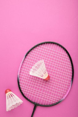 Pembe arka planda mekik horozları ve badminton raketleri. Üst görünüm.