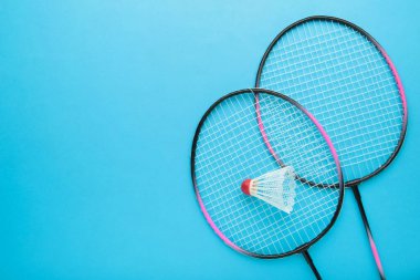 Mavi arka planda mekik horozları ve badminton raketi. Üst görünüm.