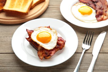 Geleneksel İngiliz kahvaltısı. Yağda yumurta, fasulye, pastırma ve gri arka planda tost. Üst görünüm
