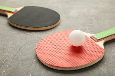 Gri arka planda pinpon raketleri ve topları. Üst görünüm