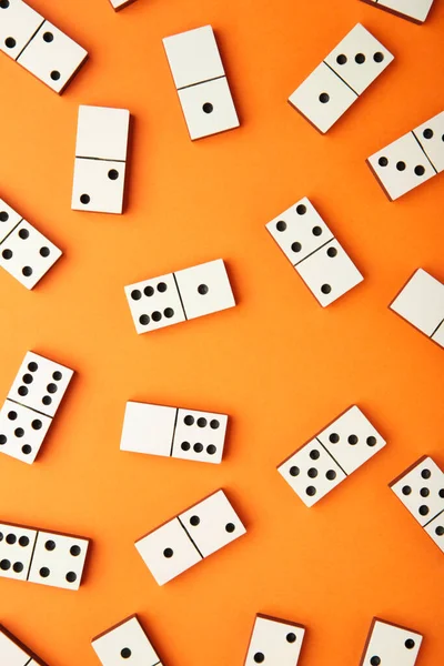Playing dominoes on a orange table. Domino effect. Vertical photo