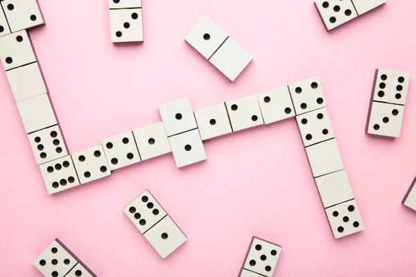 Playing dominoes on pink background. Domino effect. Top view