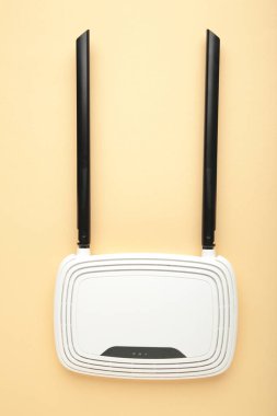Bej arka planda siyah antenli beyaz kablosuz yönlendirici ve kopyalama alanı. Minimalizm. Üst görünüm